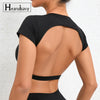 Woman wearing a black backless workout crop top with breathable, stretchy fabric — perfect for running, gym workouts, cycling, and outdoor activities.