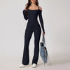 Woman wearing navy blue open-back summer jumpsuit with long sleeves and full-length legs.